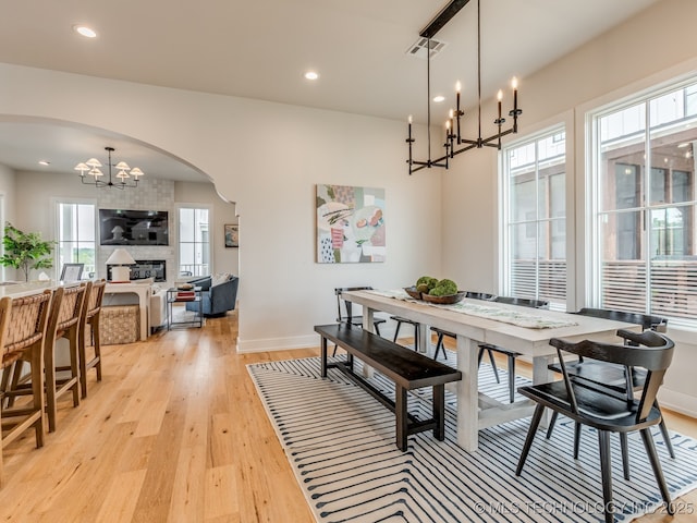56 Center Ln N, Carlton Landing, OK 74432 - dining room featuring a chandelier, arched walkways, light wood-style floors, recessed lighting, and a large fireplace