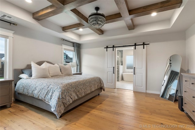 bedroom featuring coffered ceiling, a barn door, light wood-type flooring, and ensuite bath