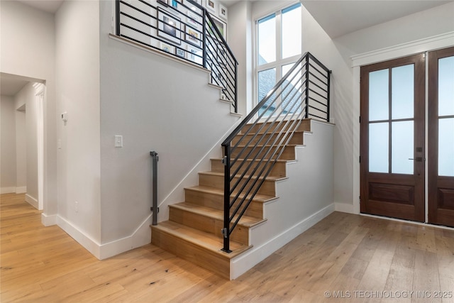 entryway with a high ceiling, french doors, and light hardwood / wood-style floors