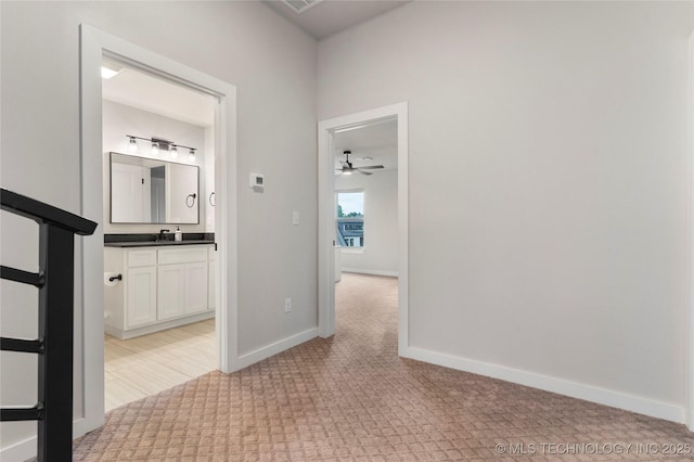 hallway featuring light carpet and sink