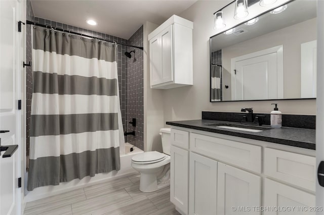 full bathroom featuring shower / tub combo with curtain, toilet, and vanity