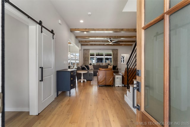 foyer entrance featuring light wood-type flooring, beamed ceiling, and a barn door