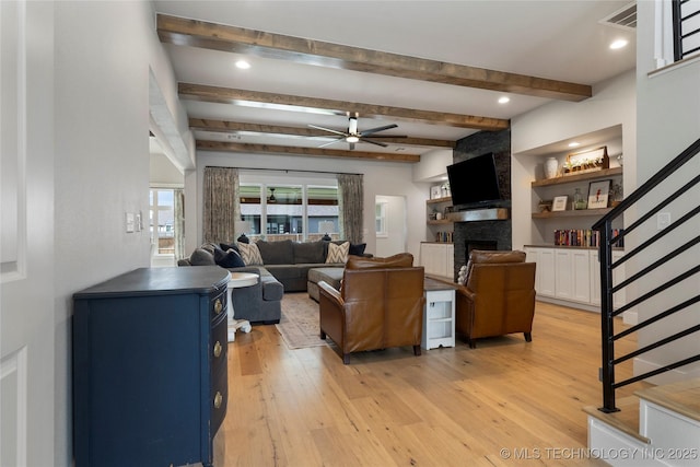 living room featuring a fireplace, light hardwood / wood-style flooring, beam ceiling, and ceiling fan