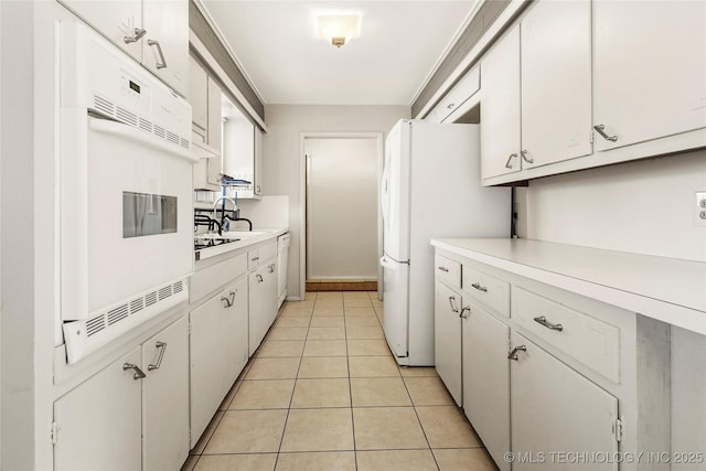 kitchen with white appliances, sink, white cabinets, and light tile patterned floors