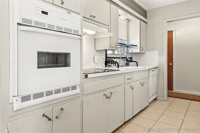 kitchen featuring white appliances, sink, white cabinets, and light tile patterned floors