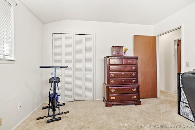 exercise room with vaulted ceiling and light colored carpet