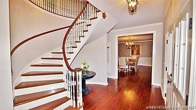 entrance foyer with crown molding, an inviting chandelier, and dark hardwood / wood-style flooring