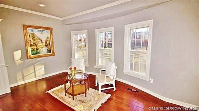 living area featuring crown molding, plenty of natural light, and hardwood / wood-style flooring