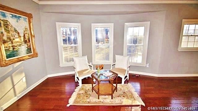 living area featuring a healthy amount of sunlight, dark wood-type flooring, and ornamental molding