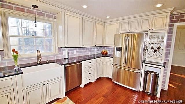 kitchen with appliances with stainless steel finishes, tasteful backsplash, sink, decorative light fixtures, and dark hardwood / wood-style flooring