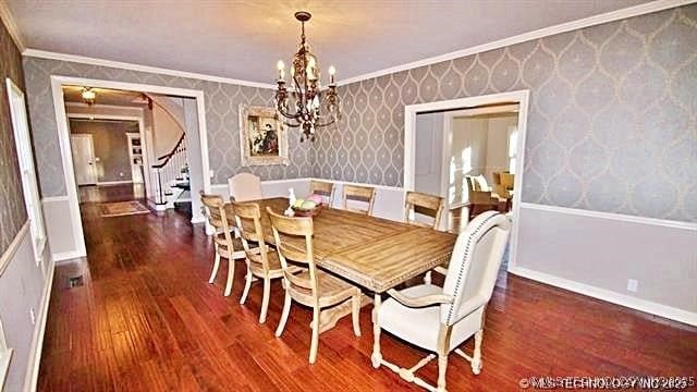 dining space featuring dark wood-type flooring, crown molding, and a chandelier