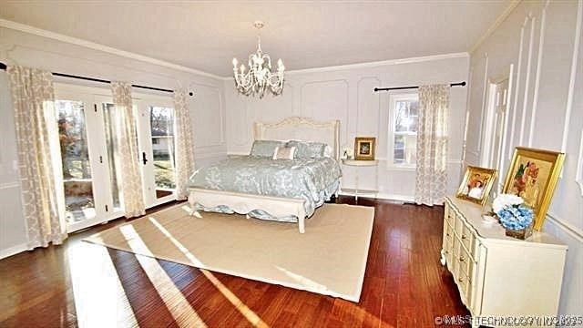 bedroom with a chandelier, ornamental molding, dark wood-type flooring, and multiple windows