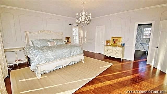 bedroom featuring a notable chandelier, ornamental molding, and dark hardwood / wood-style floors