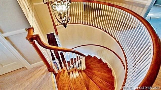 stairway with hardwood / wood-style flooring and a chandelier