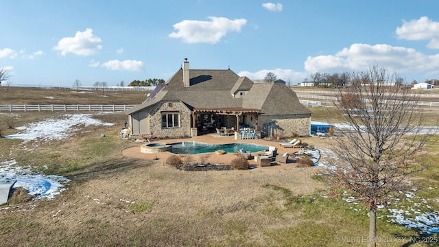 back of property featuring outdoor lounge area, a rural view, and a patio area