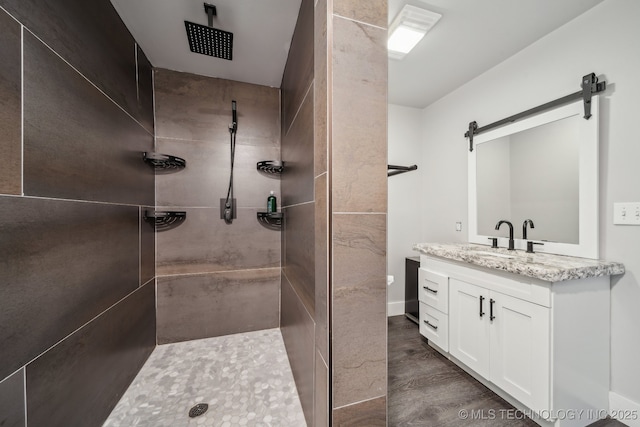 bathroom with vanity, hardwood / wood-style floors, and a tile shower