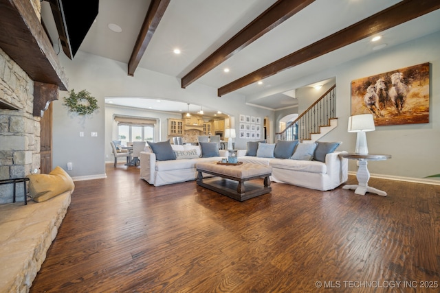 living room featuring beamed ceiling, a stone fireplace, and dark hardwood / wood-style flooring