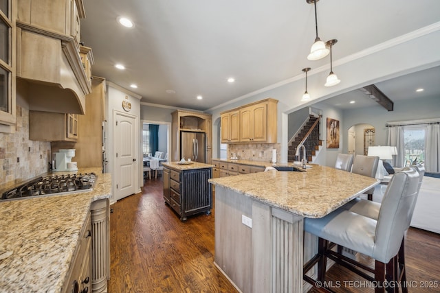 kitchen featuring a kitchen island, sink, backsplash, stainless steel appliances, and light stone countertops