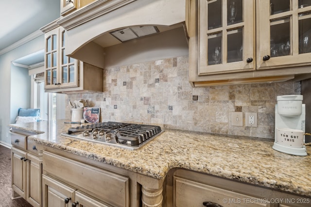 kitchen with premium range hood, stainless steel gas stovetop, tasteful backsplash, ornamental molding, and light stone countertops