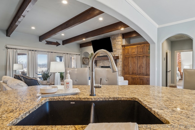 kitchen with sink, beam ceiling, and light stone countertops