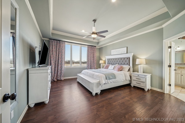 bedroom featuring ensuite bathroom, crown molding, dark hardwood / wood-style flooring, a raised ceiling, and ceiling fan