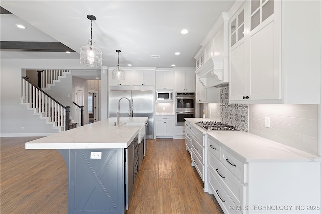 kitchen featuring pendant lighting, sink, an island with sink, and white cabinets