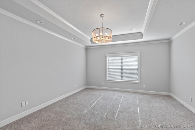 carpeted spare room with crown molding, a tray ceiling, and a chandelier