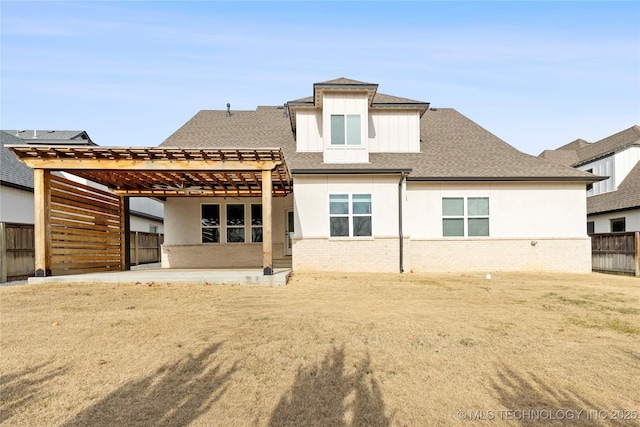 rear view of property featuring a yard, a pergola, and a patio