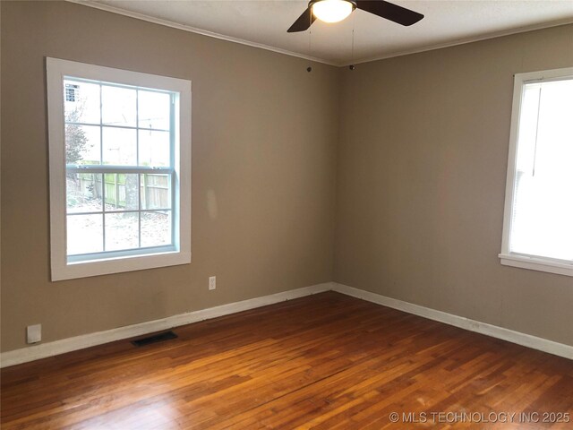 spare room featuring crown molding, a healthy amount of sunlight, and dark hardwood / wood-style floors