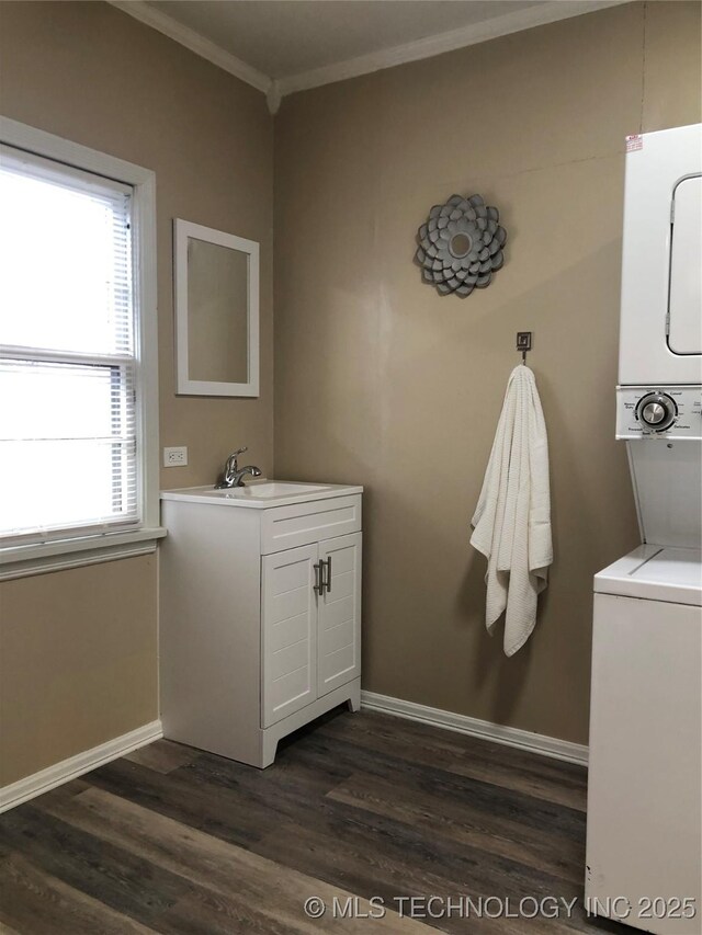 bathroom with stacked washer and dryer, vanity, hardwood / wood-style floors, and crown molding