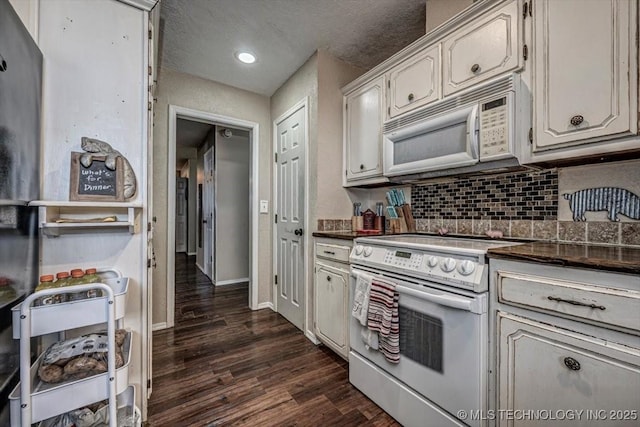 kitchen with dark wood-type flooring, a textured ceiling, white appliances, and decorative backsplash