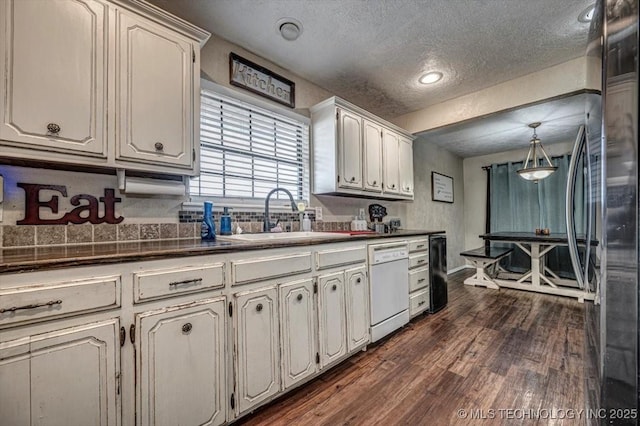 kitchen with dark wood-type flooring, sink, a textured ceiling, stainless steel refrigerator, and dishwasher