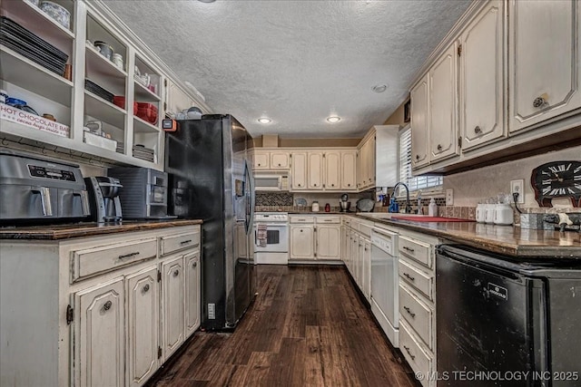 kitchen with sink, white appliances, cream cabinets, a textured ceiling, and dark hardwood / wood-style flooring