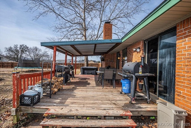 wooden deck featuring a hot tub, area for grilling, and a trampoline