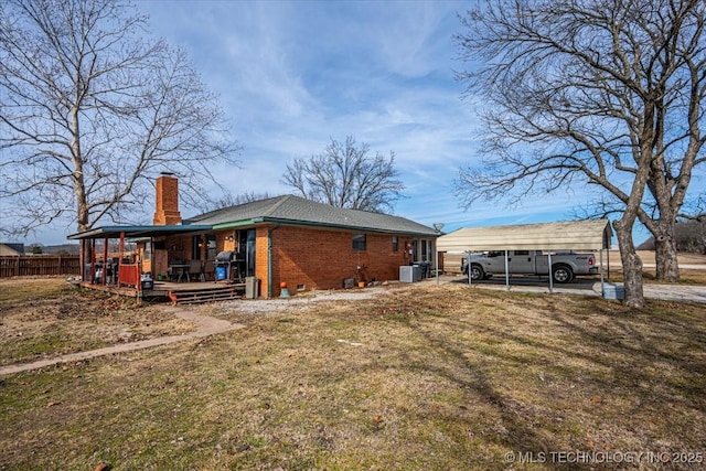 rear view of property featuring central AC unit, a yard, and a carport