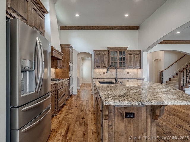 kitchen with a spacious island, stainless steel appliances, beam ceiling, and tasteful backsplash