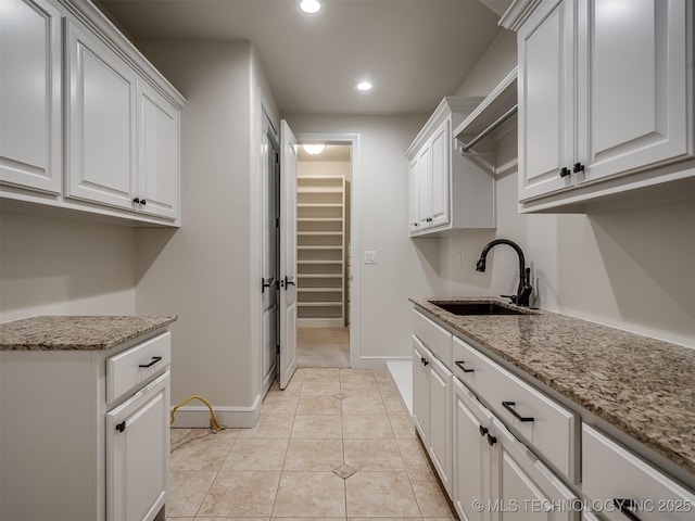 kitchen featuring white cabinetry, sink, light stone counters, and light tile patterned floors