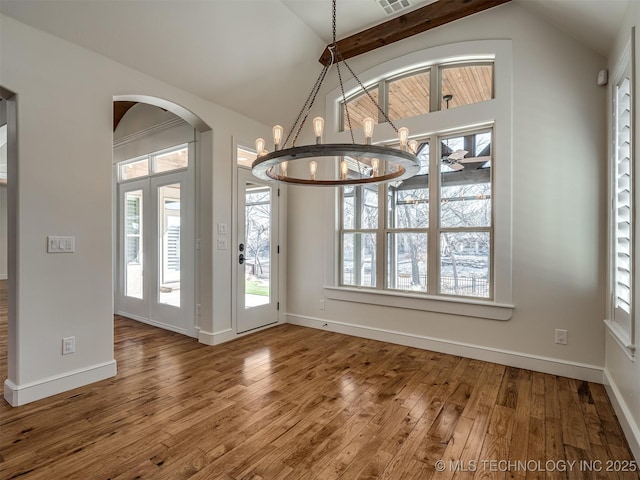 unfurnished dining area with lofted ceiling with beams, plenty of natural light, and hardwood / wood-style floors