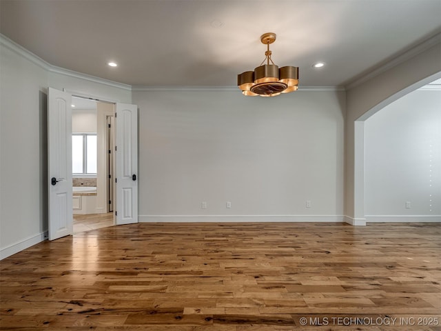 empty room featuring crown molding, wood-type flooring, and an inviting chandelier