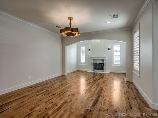 unfurnished living room with hardwood / wood-style flooring, ornamental molding, and an inviting chandelier