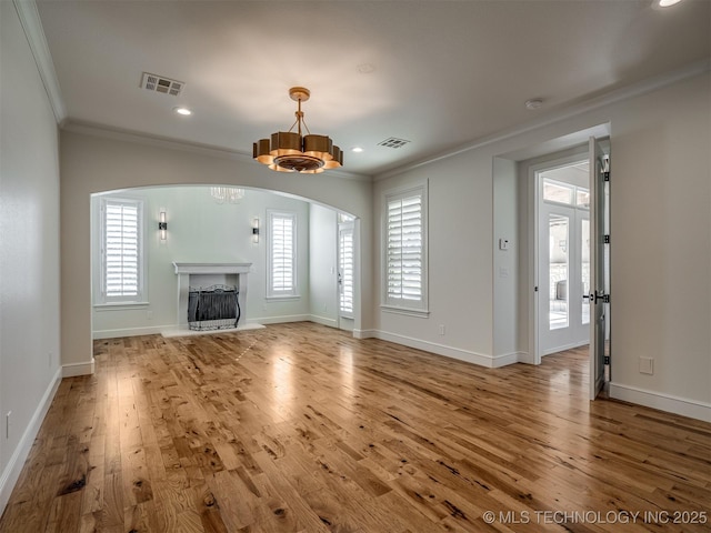 unfurnished living room with crown molding, a chandelier, and hardwood / wood-style floors