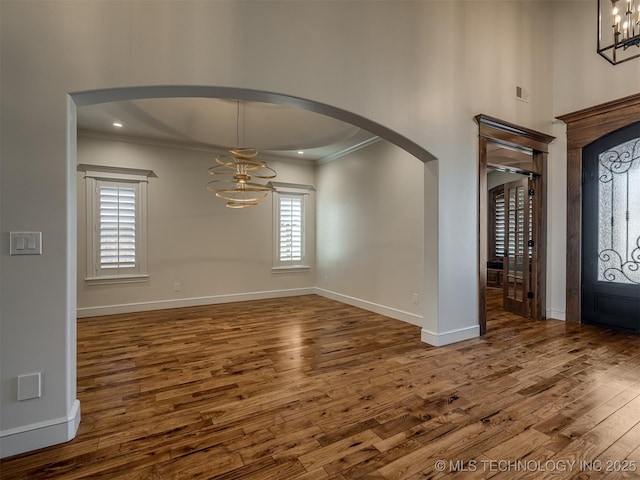 entryway featuring crown molding, dark wood-type flooring, and a notable chandelier