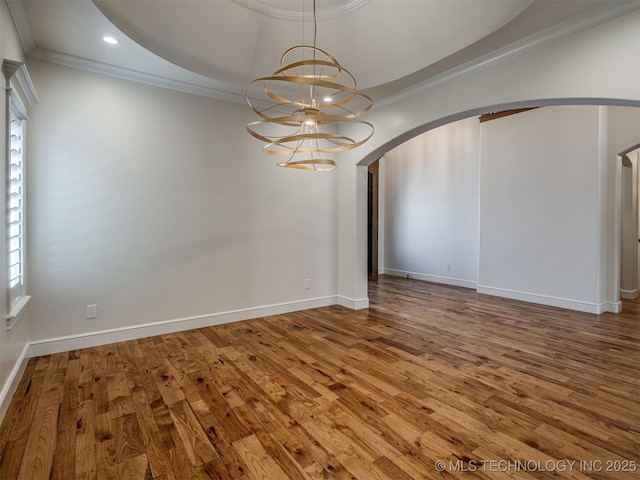 unfurnished dining area with a notable chandelier, wood-type flooring, and ornamental molding