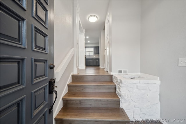 stairs featuring hardwood / wood-style flooring and sink