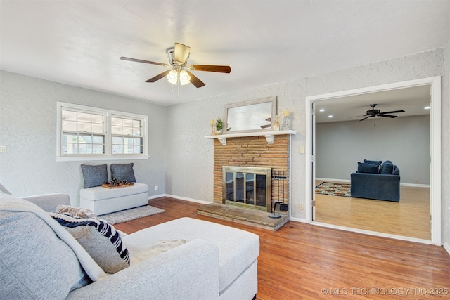 living room featuring hardwood / wood-style flooring, a fireplace, and ceiling fan