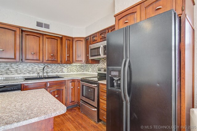 kitchen featuring appliances with stainless steel finishes, sink, dark wood-type flooring, and decorative backsplash