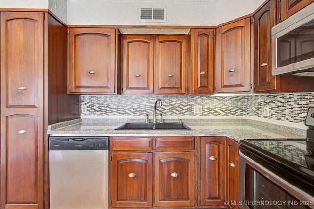 kitchen with tasteful backsplash, appliances with stainless steel finishes, and sink