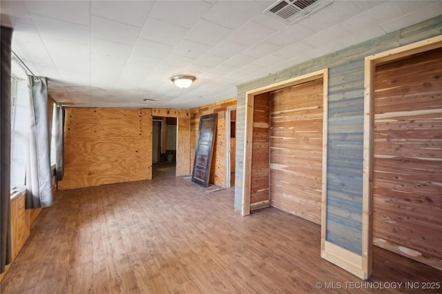 unfurnished room featuring wood-type flooring and wooden walls