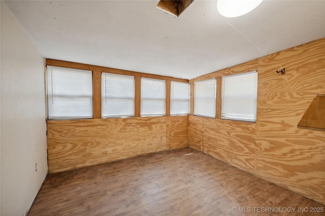 unfurnished room with wood walls and wood-type flooring