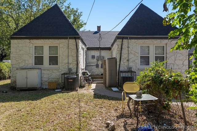 rear view of house with cooling unit and a lawn